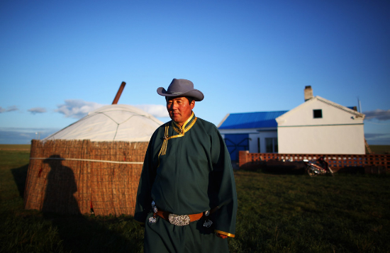 A Mongol herdsman named Gegenhasi stands in front of his new house to welcome guests in the Huhenuoer Grassland on August 27, 2009 in Hulun Buir, Inner Mongolia Autonomous Region, China. Hulun Buir, with an area of 250,000 sq km located in northeastern Inner Mongolia, is inhabited by 36 ethnic groups, including Mongolians, Daurs, Ewenkis, Oroqens, and Russian ethnicities. The vast Hulun Buir Grassland is one of the four largest natural steppes in the world. (Feng Li/Getty Images).